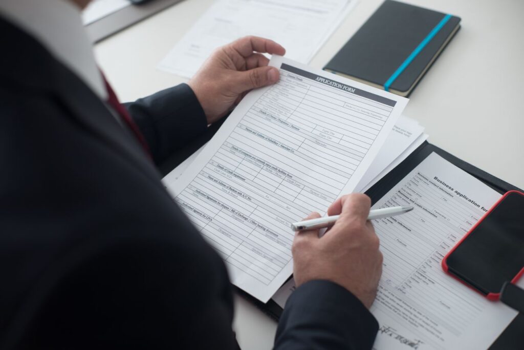 Hombre revisando un formulario de solicitud con pluma sobre el escritorio